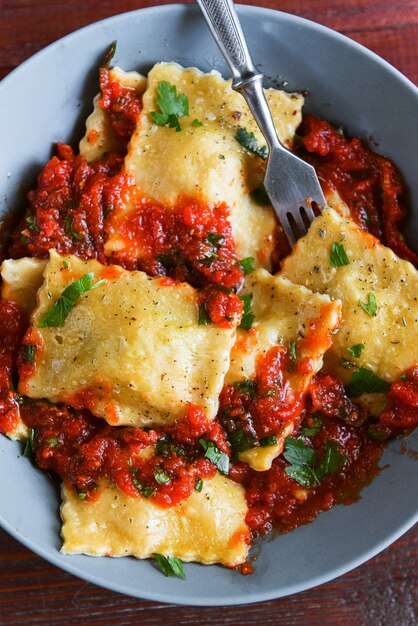 Deliciosos ravioles con salsa de tomate en un plato sobre un fondo de madera