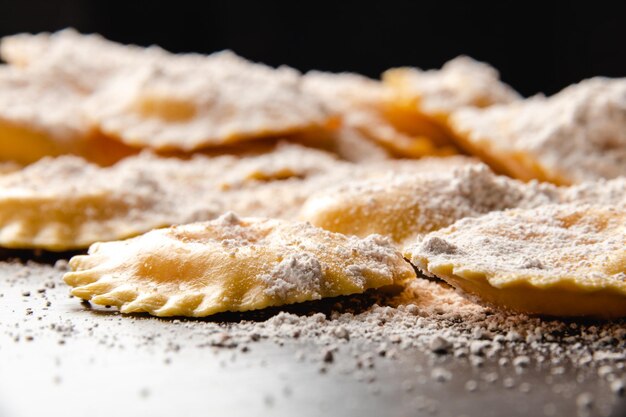 Foto deliciosos raviolis crus com farinha e manjericão em uma mesa de madeira