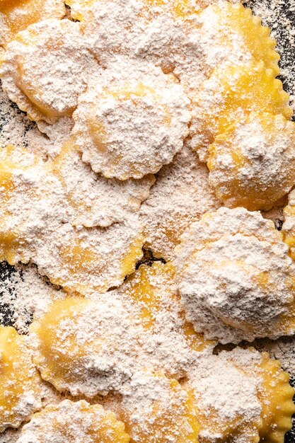 Foto deliciosos raviolis crus com farinha e manjericão em uma mesa de madeira