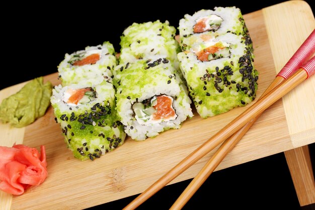 Deliciosos rollos servidos en plato de madera aislado en negro