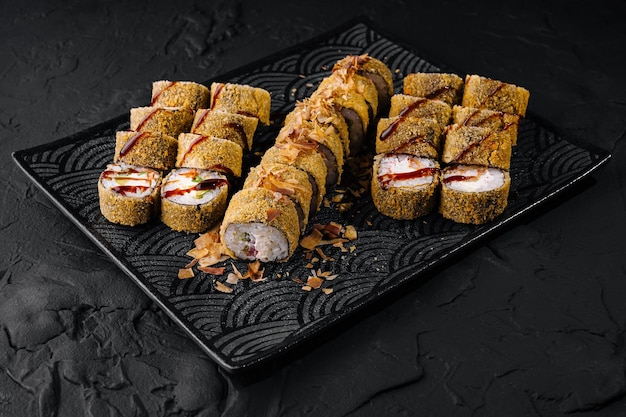 Deliciosos rollos de sushi en un elegante plato negro