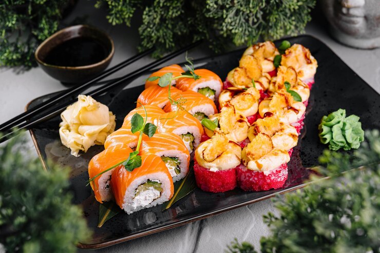 Deliciosos rollos de sushi servidos en un plato con salsa de soja y wasabi