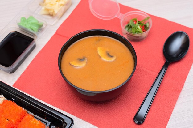 Deliciosos rolos de sopa japonesa tom yum com queijo salmão abacate pepino em embalagem para viagem com varas de madeira e molho de soja Foco seletivo Comida asiática e conceito de entrega Alimentação saudável