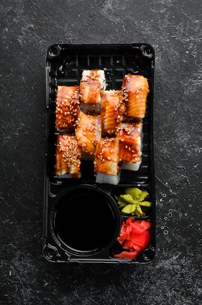 Deliciosos rolos de sushi japonês com enguia e queijo Filadélfia Entrega de comida em caixas plásticas Vista superior