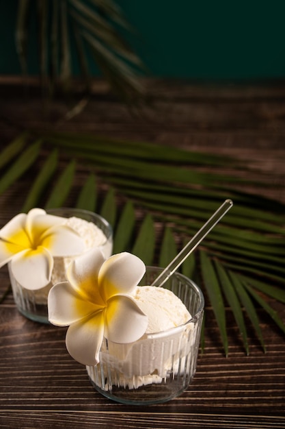 Deliciosos sabores tropicales helado sorbete decorado flor plumeria frangipani y hoja de palma en el fondo Concepto de comida de verano