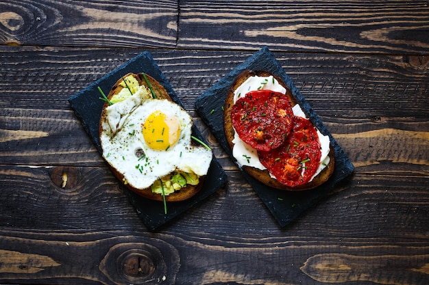 Deliciosos sabrosos huevos de aguacate y tostadas de queso con tomate