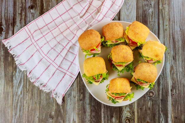 Deliciosos sanduíches na chapa branca na superfície de madeira