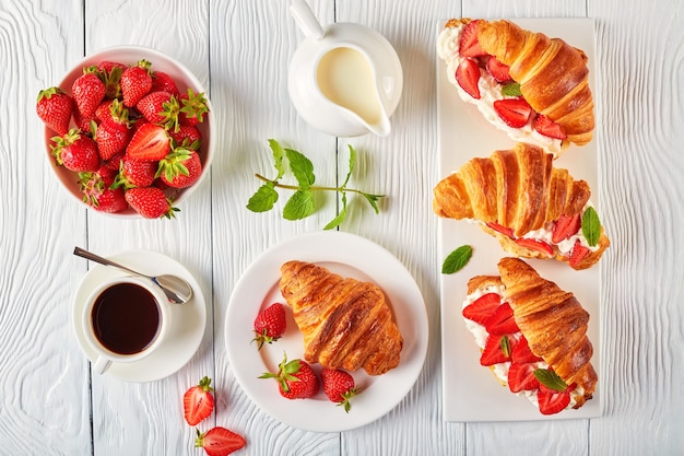 Deliciosos sándwiches de croissant con fresas frescas maduras y queso crema en un plato