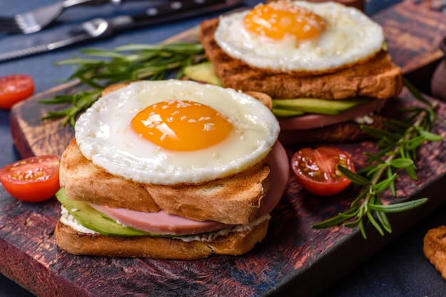 Deliciosos sándwiches frescos con huevo frito jamón mantequilla aguacate y semillas de sésamo