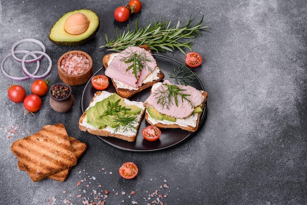 Deliciosos sándwiches frescos de mantequilla de jamón, aguacate y semillas de sésamo en una tabla de cortar de madera