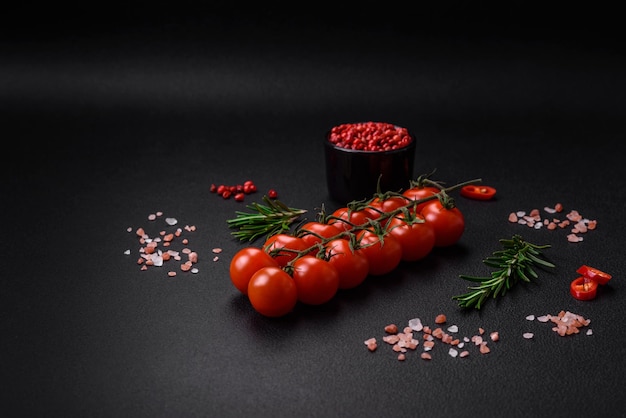 Deliciosos tomates cereja frescos em um galho em um fundo escuro de concreto