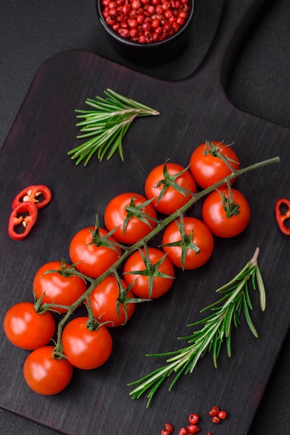 Deliciosos tomates cereja frescos em um galho em um fundo escuro de concreto