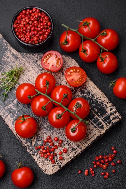Deliciosos tomates cherry frescos en las ramas como ingrediente para cocinar un plato vegetariano sobre un fondo de hormigón oscuro