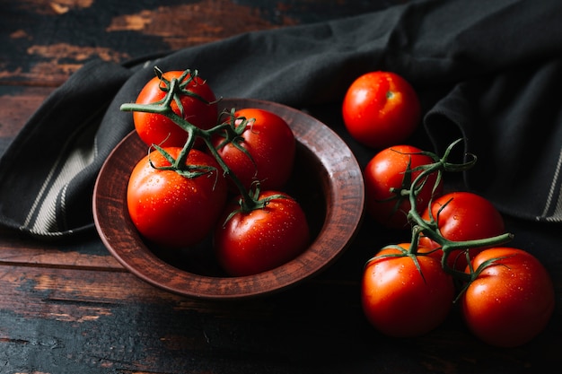 Deliciosos tomates frescos com hastes na mesa de madeira