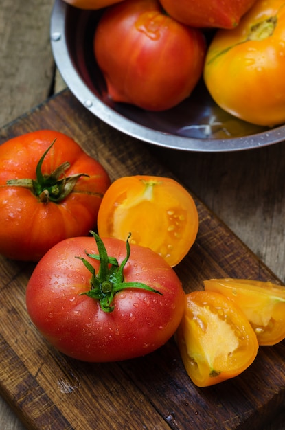 Deliciosos tomates vermelhos e amarelos na mesa de madeira