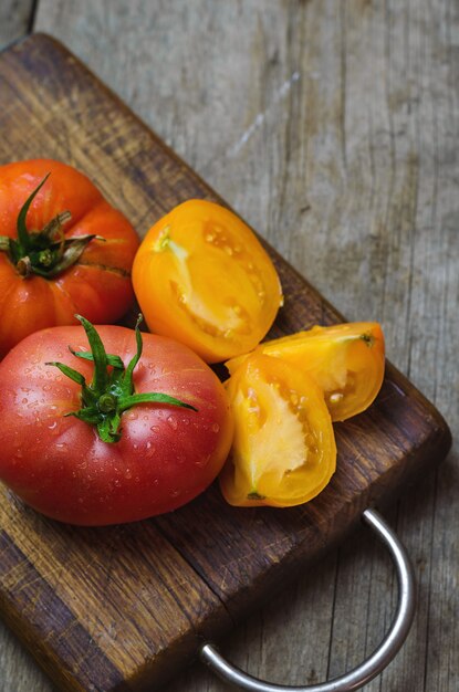 Deliciosos tomates vermelhos e amarelos na mesa de madeira.