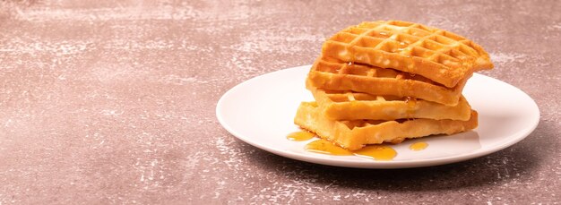 Deliciosos waffles belgas com mel servido em prato branco e conceito rústico de fundo de madeira xA