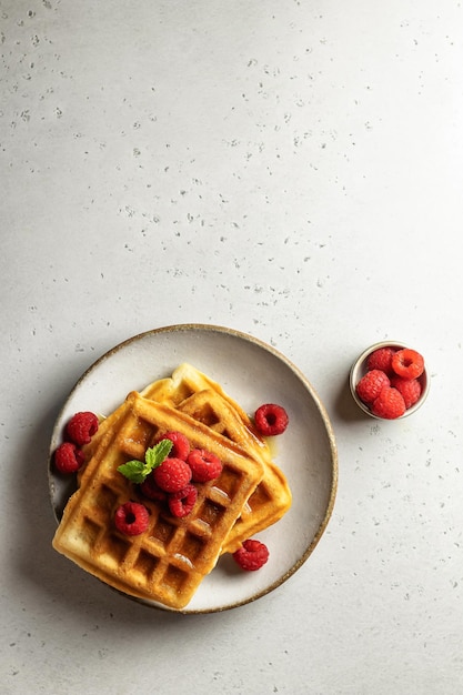 Deliciosos waffles caseiros com framboesas em um fundo branco Vista superior do conceito de café da manhã