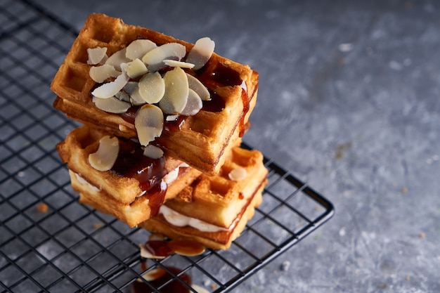 Deliciosos waffles caseiros de Viena com calda e migalhas de amêndoa, servidos em uma mesa cinza