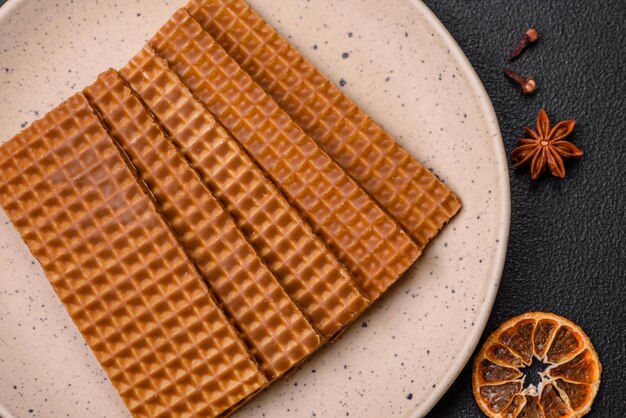 Foto deliciosos waffles retangulares crocantes e doces em uma placa de cerâmica sobre um fundo escuro de concreto