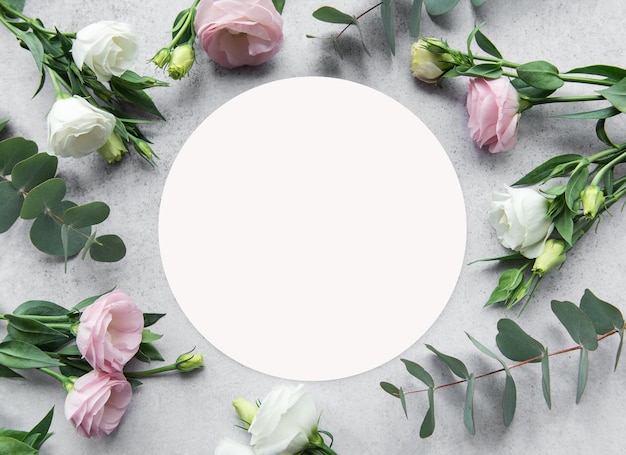 Delikate Anordnung von rosa und weißen Blumen, die einen leeren Kreis auf einer strukturierten Oberfläche umgeben