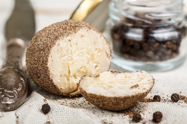 Delikatesse runder kleiner Käse mit schwarzem Pfeffer und Knoblauch. Belper knolle