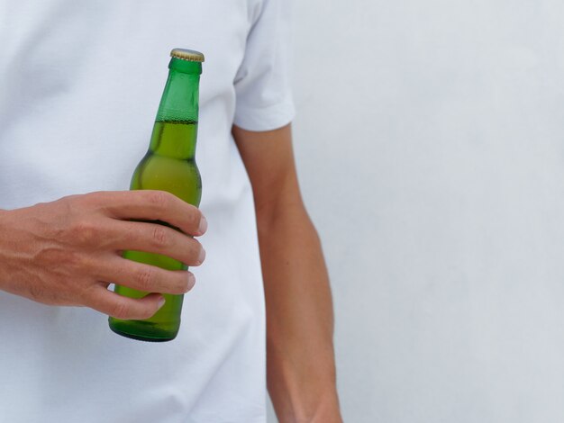 Delimitar imagen. Hombre de camiseta blanca con botella de cerveza. Copia espacio