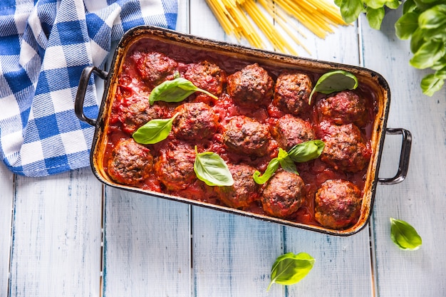 Delisante italienische Mahlzeit Fleisch Rindfleischbällchen mit Pasta Spaghetti und Basilikum in Vintage Bräter.