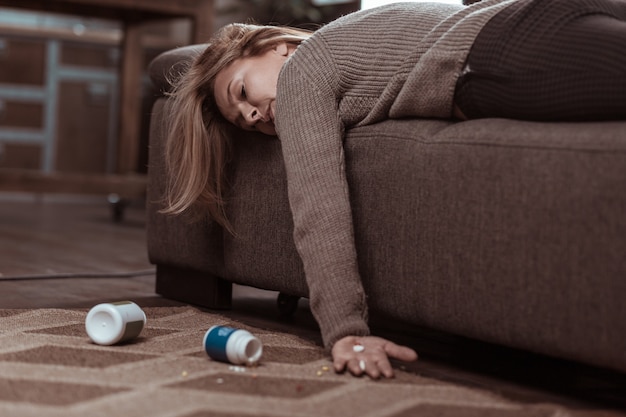 Demasiadas pastillas. Mujer de familia madura de pelo rubio que se queda dormido después de tomar demasiadas pastillas