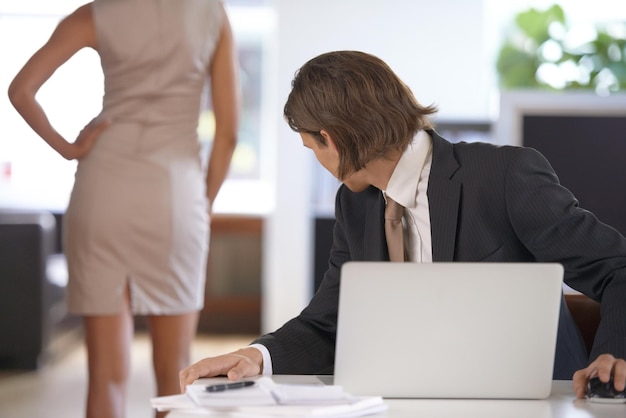 Demasiado atractivo para no mirar Joven mirando a un compañero de trabajo detrás en el trabajo