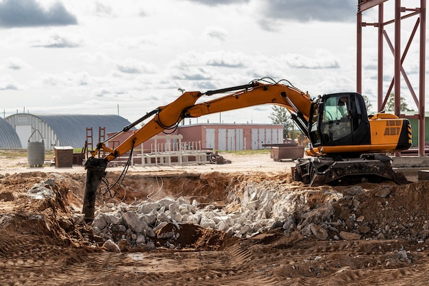 Demolição profissional de estruturas de concreto armado com martelo hidráulico industrial com escavadeira. Varas de acessórios de metal. Destroços e pedaços de concreto.