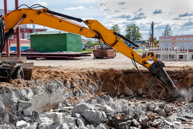 Foto demolición profesional de estructuras de hormigón armado mediante martillo hidráulico industrial con excavadora. varillas de fornitura de metal. escombros y desmoronamientos de hormigón.