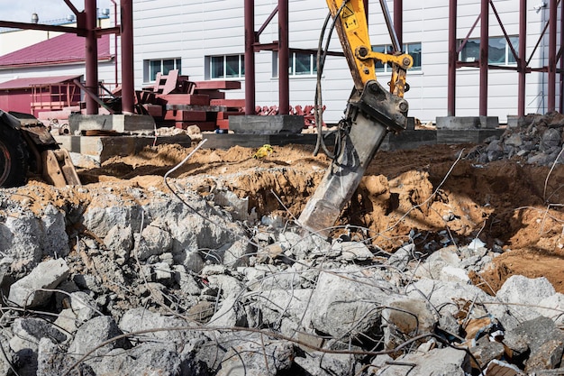 Foto demolición profesional de estructuras de hormigón armado mediante martillo hidráulico industrial con excavadora. varillas de fornitura de metal. escombros y desmoronamientos de hormigón.
