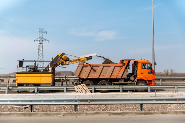 Demontage der Asphaltdecke recycelte Asphaltkrümel werden in den LKW-Aufbau gegossen