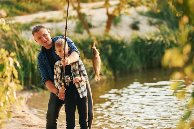 Den Fang halten Vater und Sohn beim gemeinsamen Angeln im Freien im Sommer