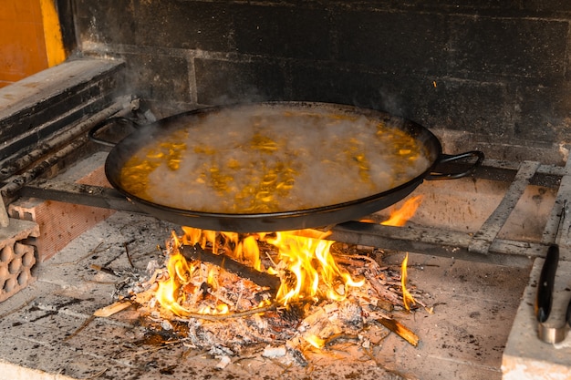 Den Reis der valencianischen Paella mit Glut und Gemüse kochen