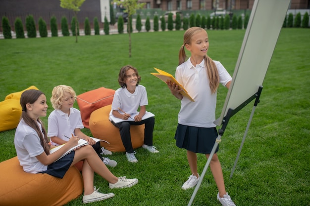 Denken. Blondes Mädchen, das nahe dem Flipchart steht und nachdenklich aussieht