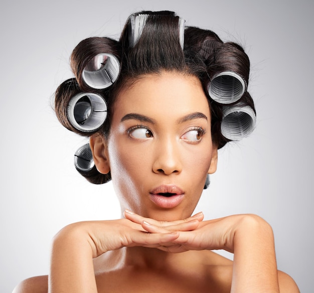 Denkende Frau und Haarroller im Studio mit Händen wow Emoji und Schönheit oder Glanz Idee Schock und Modell Mädchen mit weißem Hintergrund für Kosmetik Selbstpflege und Morgenroutine mit Überraschung