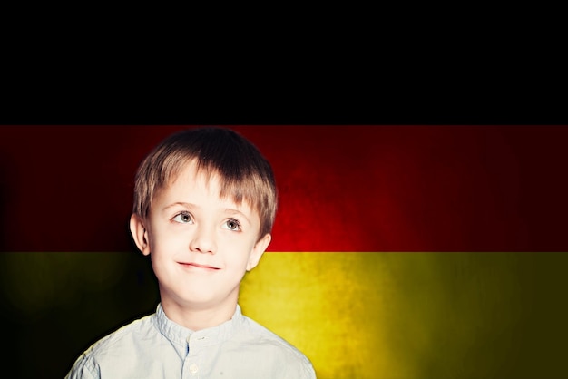 Denkender Kind-Jungen-Student vor dem Hintergrund der Deutschland-Flagge