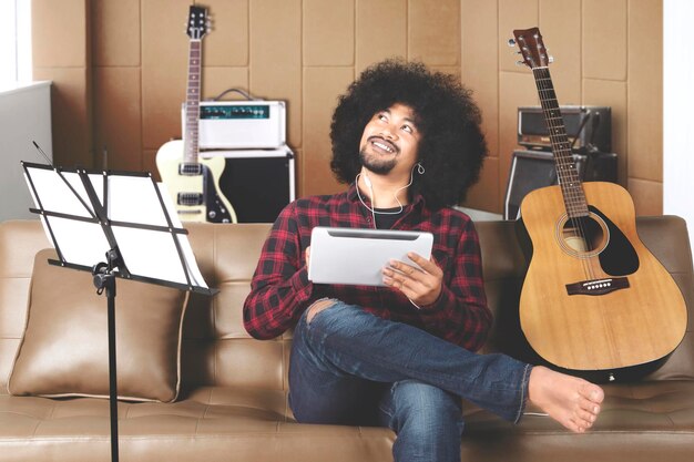 Denkender Musiker mit digitalem Tablet im Aufnahmestudio