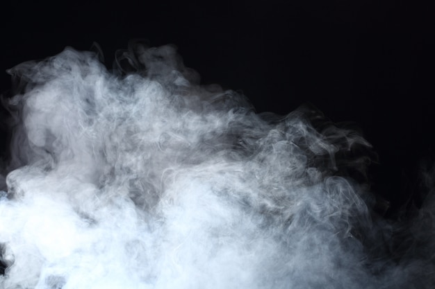 Densas bocanadas esponjosas de humo blanco y niebla sobre fondo negro