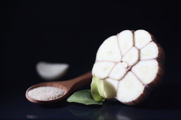 Dente de alho fresco em fundo preto. o alho é rico em vitaminas, primavera útil, bons temperos. alho cortado em um fundo escuro. alho fatiado cru.