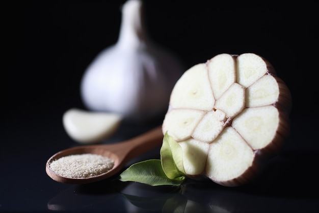 Dente de alho fresco em fundo preto. O alho é rico em vitaminas, primavera útil, bons temperos. Alho cortado em um fundo escuro. Alho fatiado cru.