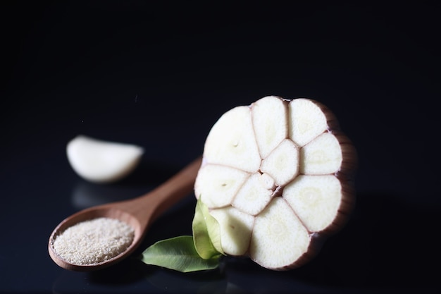 Dente de alho fresco em fundo preto. O alho é rico em vitaminas, primavera útil, bons temperos. Alho cortado em um fundo escuro. Alho fatiado cru.