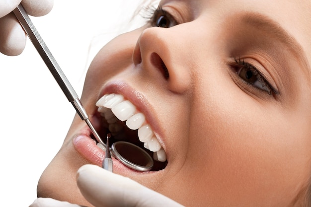 Dentes de mulher e um espelho bucal de dentista no fundo
