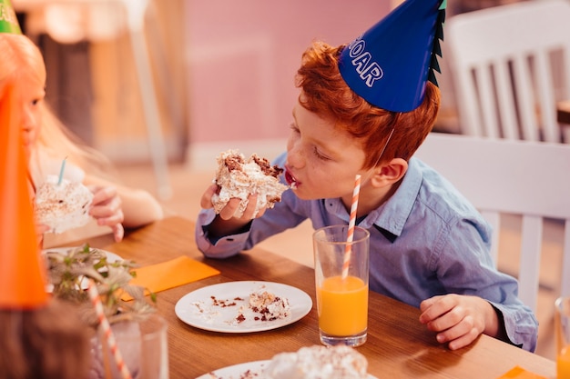 Dentes doces. criança ocupada com chapéu de papel durante uma visita à festa de aniversário