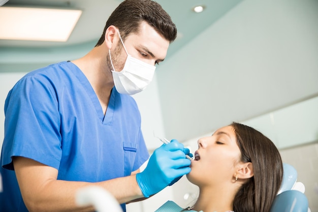 Dentista adulto medio analizando paciente adolescente con equipo dental en la clínica