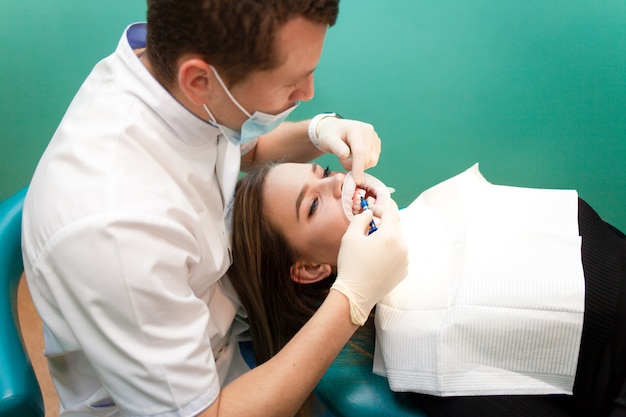 El dentista aplica gel blanqueador en los dientes del paciente.