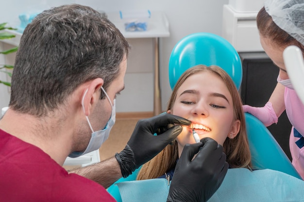 Dentista aplica o medicamento no dente do paciente, espremendo-o para fora da seringa