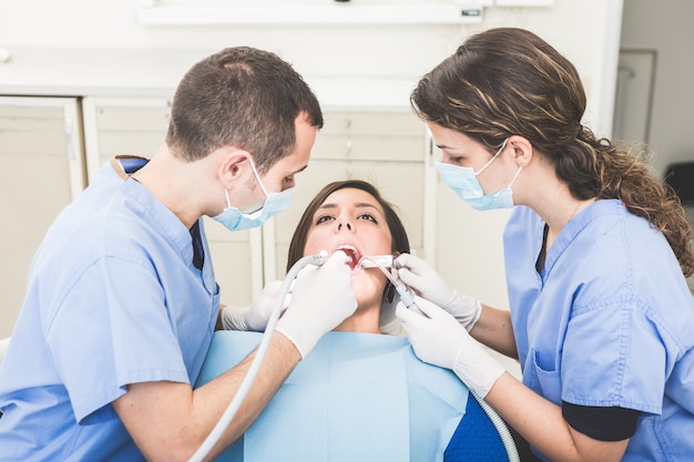 Dentista y asistente dental examinando los dientes del paciente.